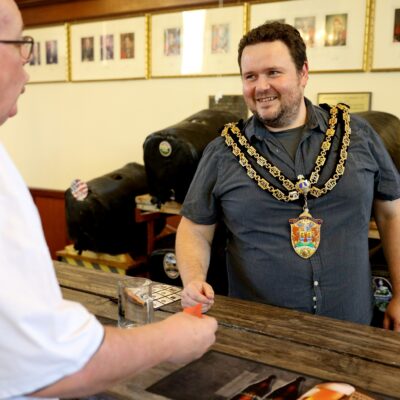 Neath Town Mayor wearing the Mayoral Chairs, standing behind the bar at the Ale and Cider festival